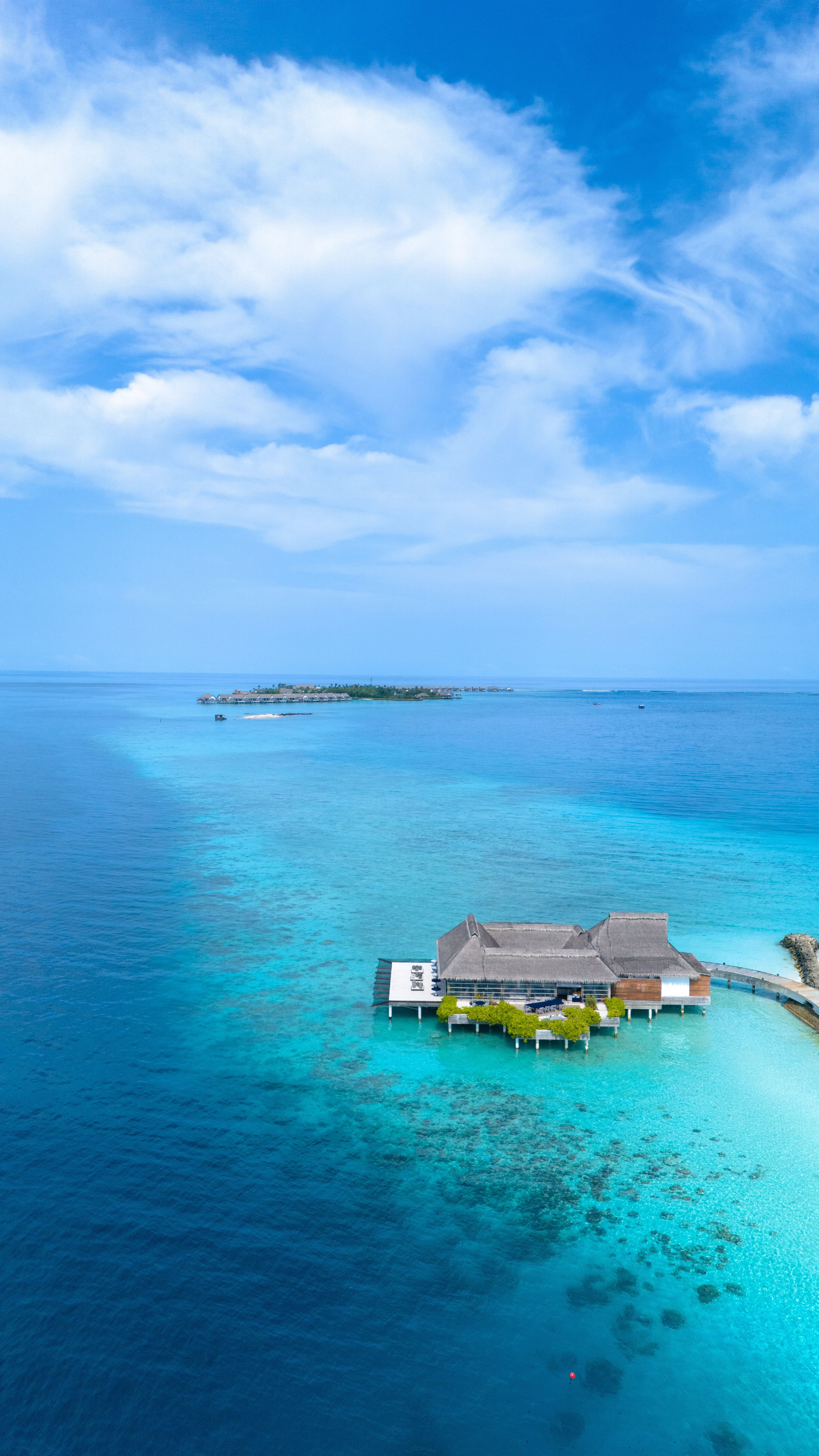 Discover serenity in this aerial view of a stunning overwater bungalow amidst the turquoise waters of Maldives island